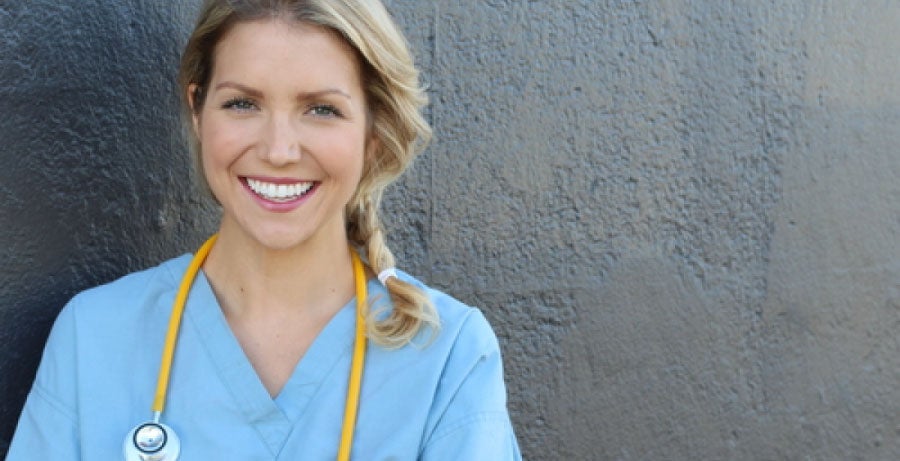 Registered nurse smiling against grey background