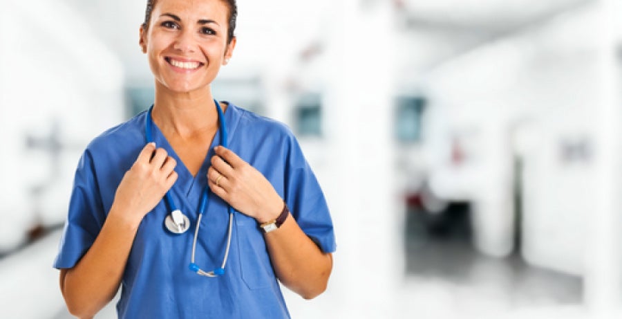 Smiling nurse in hospital corridor wearing scrubs